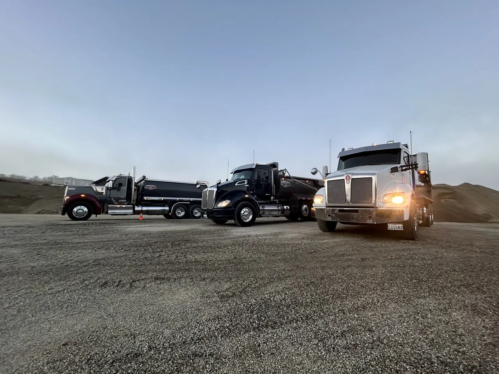Marc Cohen Trucking fleet — three Kenworth dump trucks at a job site